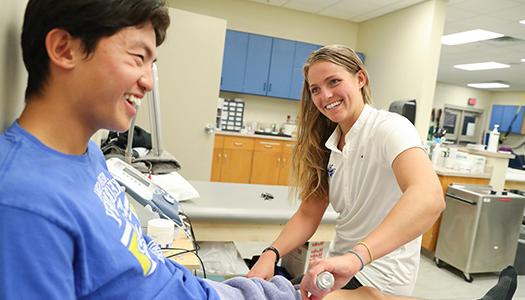 an athletic training student helps a patient recover in a clinic